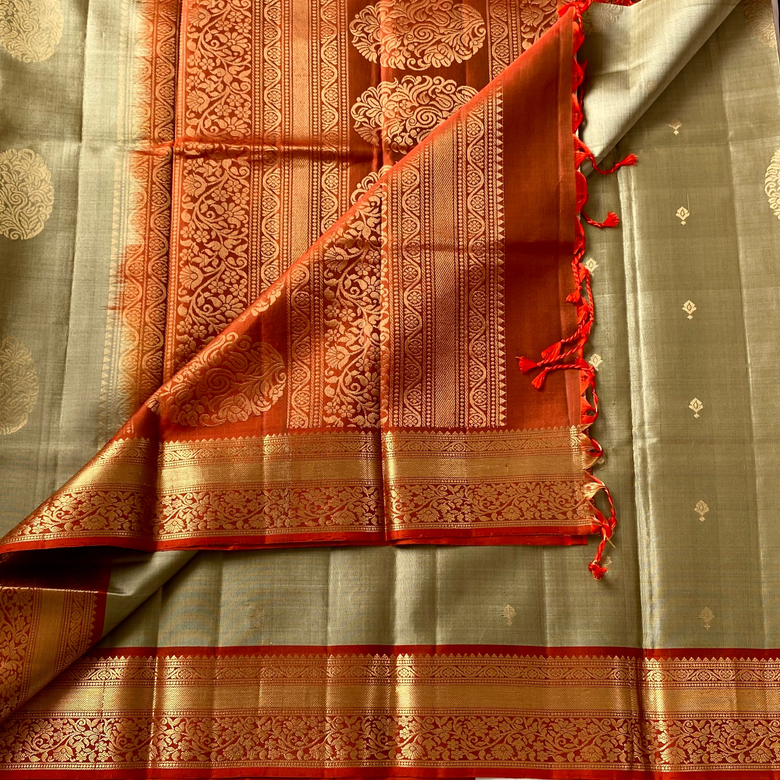 Metallic Greyish beige with stunner orange masterpiece with zari woven buttas