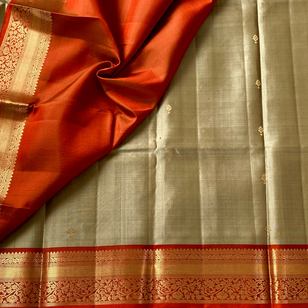 Metallic Greyish beige with stunner orange masterpiece with zari woven buttas